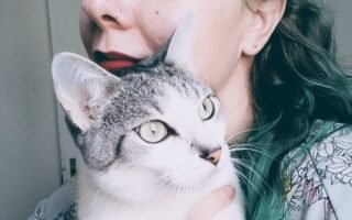 Katia está de perfil e com o seu gato no colo.