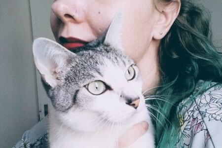 Katia está de perfil e com o seu gato no colo.